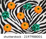 Small photo of Kitschy Halloween or Thanksgiving composition with little pumpkins and green ribbons on zebra print background.