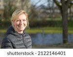 Small photo of Cute young blond woman with an impish grin in a park