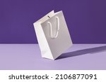 White floating paper shopping bag on purple background. Shopping sale delivery concept