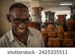 Small photo of Dar es Salaam Tanzania - Jan 26 2024: A man selling traditional charcoal powered clay cooking stoves stands at his stall inside Kisutu Market in Dar es Salaam, Tanzania in East Africa