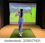 Small photo of Golfers hitting ball with golf club from indoor court. Playing golf on a golf simulator