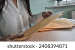 Small photo of Woman secretary unpacks mail in yellow envelopes closeup. Delivery by business mail by registered mail