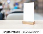 Small photo of Mock up Label the blank menu frame in Bar restaurant ,Stand for booklets with white sheets paper acrylic tent card on wooden table cafeteria blurred background can inserting the text of the customer.