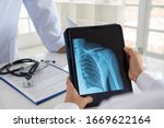 Small photo of shoulder joint x-ray image on digital tablet with doctor team medical diagnose injuries of tendons and bones.