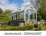 Small photo of A garden plot with seedbeds and a glass greenhouse in the center of kitchen garden. A suburban or rustic backyard for gardening. A warm summers day.Trentham gardens staffordshire