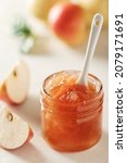 Small photo of Apple jam in a glass jar. Apple jam on a light background. Delicious natural marmalade.