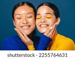 Small photo of Two young women smile and embrace each other with makeup on their faces. Female friends in their 20’s feeling self-assured as they embrace the gen z beauty trends of graphic eyeliner and eyeshadow.