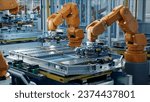 Small photo of Orange Industrial Robot Arms Assemble EV Battery Pack on Automated Production Line. Row of Advanced Robotic Arms inside Automotive Plant Assemble Batteries. Modern Electric Car Smart Factory.