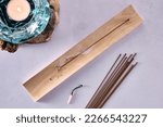 Small photo of Overhead view of burning japanese incense stick on wooden holder, incense sticks on table and tealight
