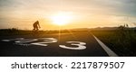 Small photo of New year 2023 or start straight and beginning concept.silhouette of Blurry Man ride on bike and word 2023 start written on the road at sunset.Concept of challenge or career path,business strategy.