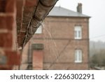 Small photo of a gutter on a building, an old drainpipe close-up, water flows through rotten metal, there is a place for an inscription