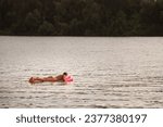 Small photo of BELGRADE, SERBIA - JULY 31, 2021: Selective blur on a young man, white caucasian, swimming and floating on an air mattress on Reka Sava River in Obrenovac, belgrade a dusk.