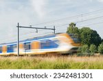 Small photo of Sprinter train rushes by at high speed, blurred by motion in Arnhem in the Netherlands