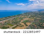 Small photo of Aerial view of calm Aegan Sea and seashore. Greek houses with orange roofs among gardens, forests, and farmlands. High quality photo