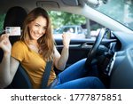 Small photo of Car interior view of woman with driving license. Driving school. Young beautiful woman successfully passed driving school test. Female smiling and holding driver's license.