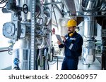 Small photo of Heating plant interior with pipes and valves and factory worker controlling process of boiling.