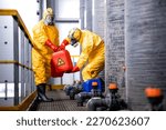 Small photo of Factory workers carefully handling toxic and dangerous biohazardous waste in chemicals factory.