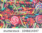 Small photo of Colorful bright assorted candy canes and rainbow colored spiral lollipops with scattered marmalade, jellybeans and different colored round candy. Top view. Candy background.