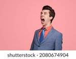 Funny angry male entrepreneur in suit shouting on pink background in studio and looking away