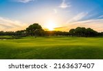 Small photo of Panorama of golf course at sunset with beautiful sky. Scenic panoramic view of golf fairway. Golf field with pines