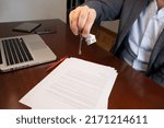 Small photo of Man signs the contract and hands over the house keys. Concept of house sale, mortgage, notary deed.