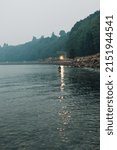 Small photo of Seattle, WA, USA - August 20, 2018: BNSF freight train traveling through Carkeek Park during a smoky evening with single man fishing in puget sound