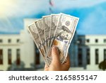 dollars in a man's hand on the background Federal Reserve Building in Washington DC, United States, FED