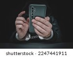 Small photo of Ill-intended fraudster uses mobile. Fraudster calls. . Hacker hijacks by phone. Cellphone account fraud. Scam. handcuffs on the hands of a telephone fraudster. arrest of a bandit