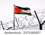 Small photo of View of palestinian flag behind barbed wire against cloudy sky. border post on the border of palestine. The checkpoint at the embassy of the country. the Palestinian-Israeli border.