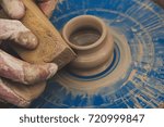 Small photo of Potter from the clay pitcher on a Potter's wheel. Man cleans with sponge pottery on a Potter's wheel. The final stage of manufacture of the jug