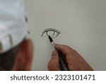 Small photo of Paris, France - 06 24 2023 : A draftsman draws a person's eyes