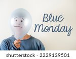 Small photo of Woman dressed in blue with a balloon on her head with a sad face drawn on her head. written text "Blue Monday"