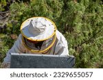 Small photo of detail of beekeeper in protective suit extracting panels in beehive, protective hat with visor and beekeeper's hat with visor, and beekeeper's hat with visor and beekeeper's hat on nature