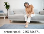 Small photo of senior woman suffering from knee ache on sofa