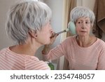 Small photo of Mischievous senior woman playing with a plunger