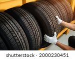 Close to the hands of a tire changer in Large warehouse of car tires, rack with customer car tires in warehouse of a tire dealer