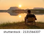 A young man sitting on a chair at mountain lake with relaxing mood, lonely man, Asian man travel alone. 