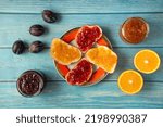 Small photo of Orange and plum fruit jam in a glass jars on a wooden blue table, mix jam, various jams, type jam, different jams, Assortment of summer seasonal orand and pium and fruits jams in small jars