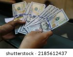 Small photo of Bandung, Indonesia, Jan 8 2015: One Hundred Dollars. Portrait of a customer's hand holding US Dollars in one of the money changers. The money amounted to more than a thousand US Dollars