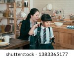 Small photo of young mother worker in business suit help daughter get ready for school. Mom support child to wear backpack bag in wooden kitchen talking nag to little girl after breakfast time leaving home to study