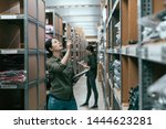 Small photo of female coworkers taking inventory in logistics warehouse. young girl team partners standing in stockroom working. two woman staffs stocktaking by using tablet and clipbaord indoor in clothes factory