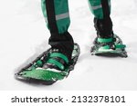 Man walks in green snowshoes....