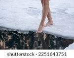 Small photo of close-up view of girl legs standing on snow near ice hole getting into cold water in winter, healthy lifestyle, tempering concept