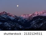 Small photo of A Purple and blue sunset in the Rocky Mountains. A full moon hangs overtop of the mountains