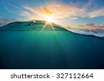 Abstract ocean design template with underwater part and sunset skylight splitted by waterline. Beautiful clouds and bright sun over sea water.