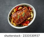 Small photo of bowl of whole roast pork and vegetables on dark grey kitchen table, top view