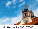 View of the sharp towers of the Church of Mother of God before Týn and red tiled roof against vibrant blue sky and white couds. Prague, Chezh Republic