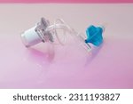 Small photo of Disposable tracheostomy tube with cuff, cuff inflation line and balloon for establishment of artificial airway and breathing support on light rose background