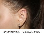 Small photo of Girl's ear. Ear cartilage piercing + a ring with a scattering of transparent cubic zirkonia and a lobe piercing.