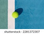 Small photo of Tennis ball on a white line on hard tennis court of blue color. Flat lay, top view, copy space. Summer sport. Tennis court with a tennis ball close up. Summer activities and active life concept